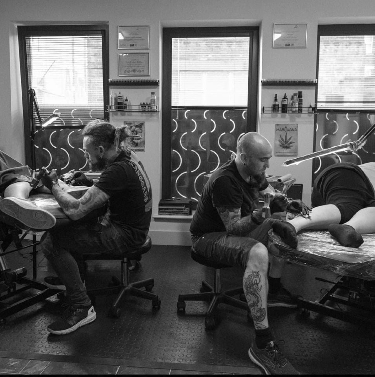 Inside Rocky Ink & Piercing studio, artists tattooing clients under work lamps in Whitechapel