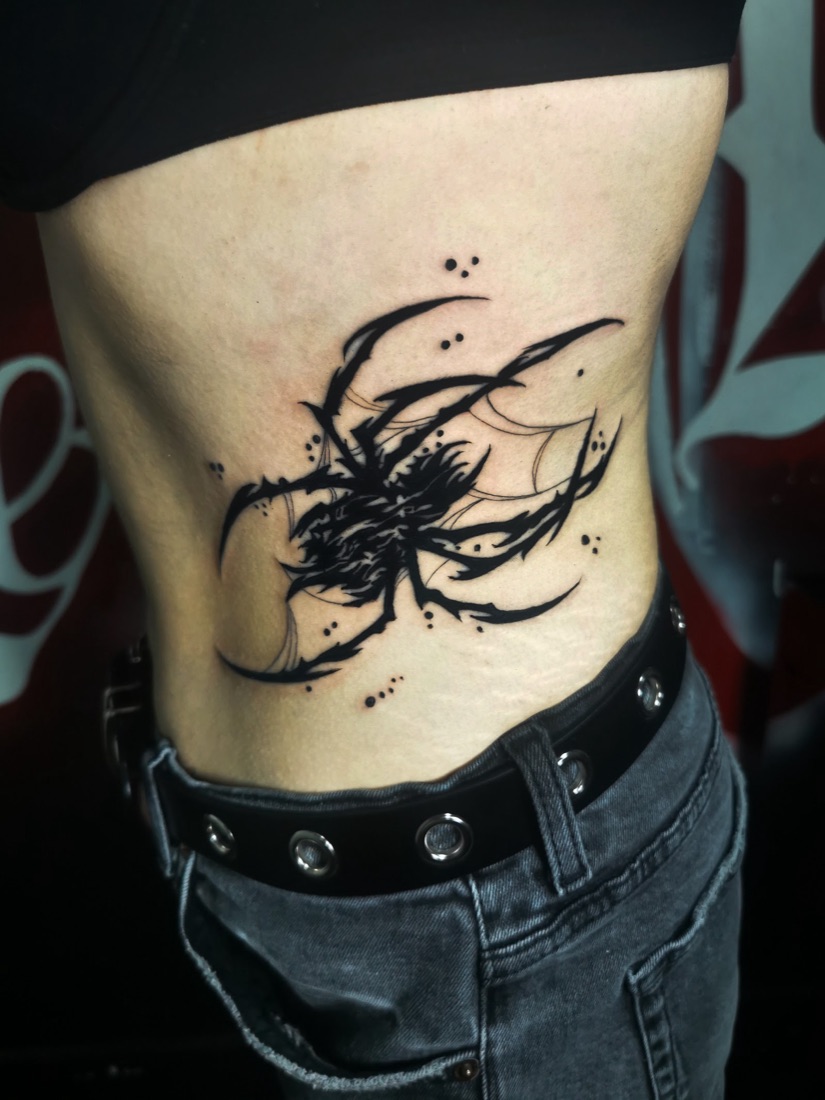 Freehand blackwork abstract tattoo across the ribs