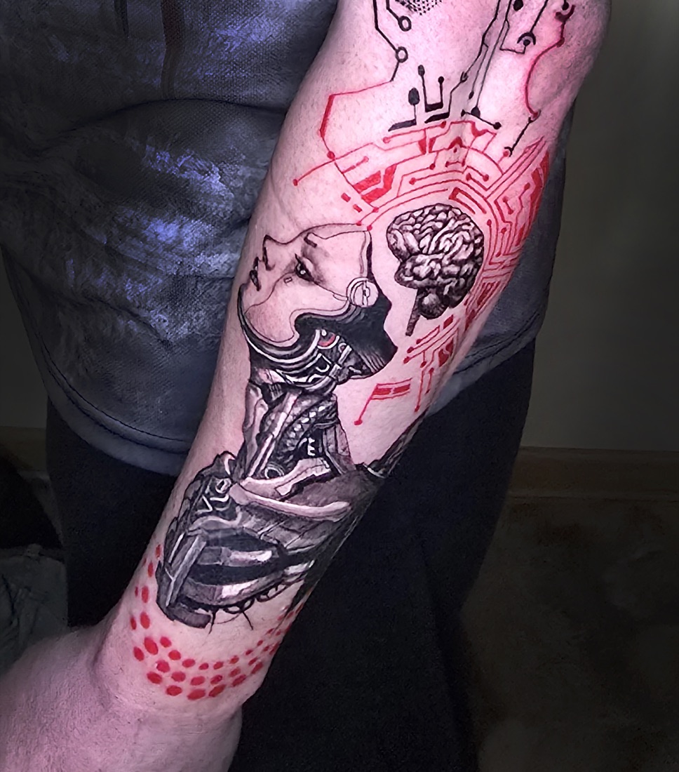 Colour and black cyber portrait tattoo with red circuitry on the forearm